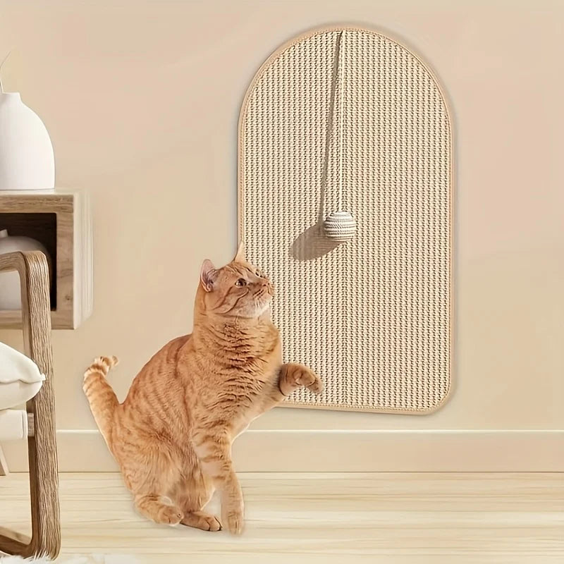 Chat roux tigré assis, patte levée vers la balle suspendue d'un tapis à gratter en sisal accroché au mur