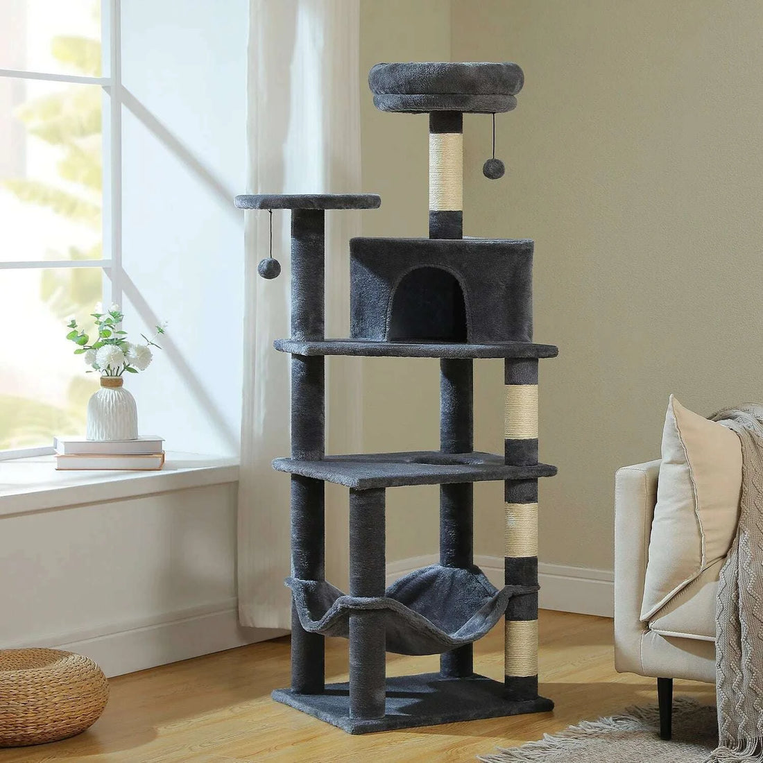 Arbre à chat gris foncé dans un salon près de la fenêtre, avec poteaux en sisal et hamac