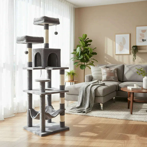 Grand arbre à chat gris avec hamac et niche dans un salon lumineux, près d'un canapé gris et d'une plante verte