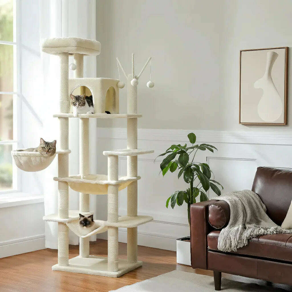 Grand arbre à chat crème dans un salon lumineux, près d'un canapé en cuir, avec trois chats