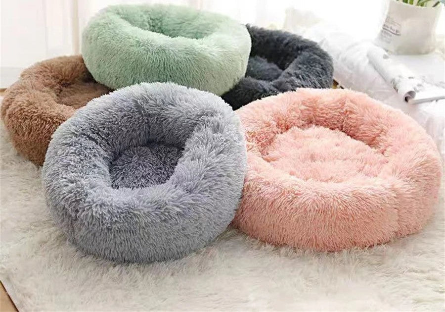 Cinq paniers ronds moelleux posés sur un tapis blanc : marron, vert menthe, gris foncé, gris clair et rose