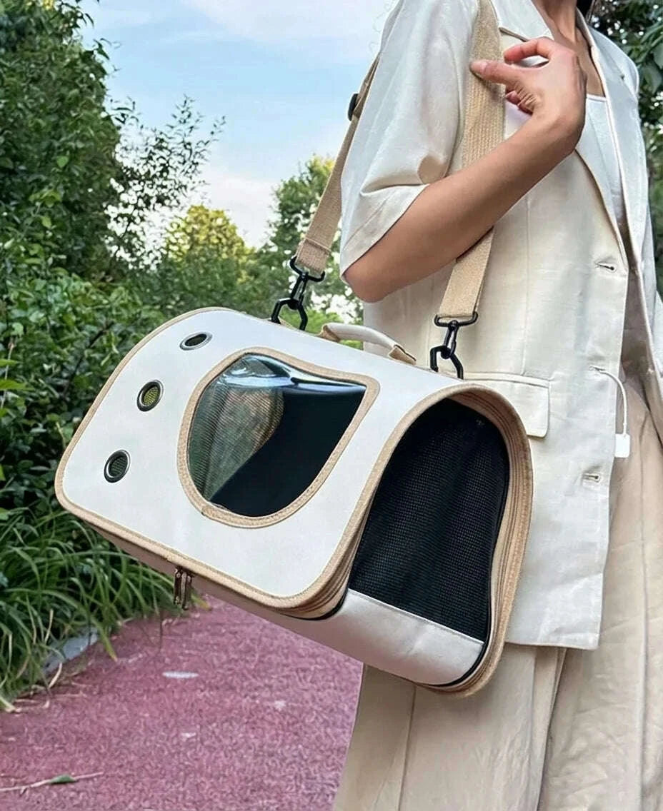 Femme portant en bandoulure un sac de transport beige pour chat, avec filet d'aération latéral et hublot