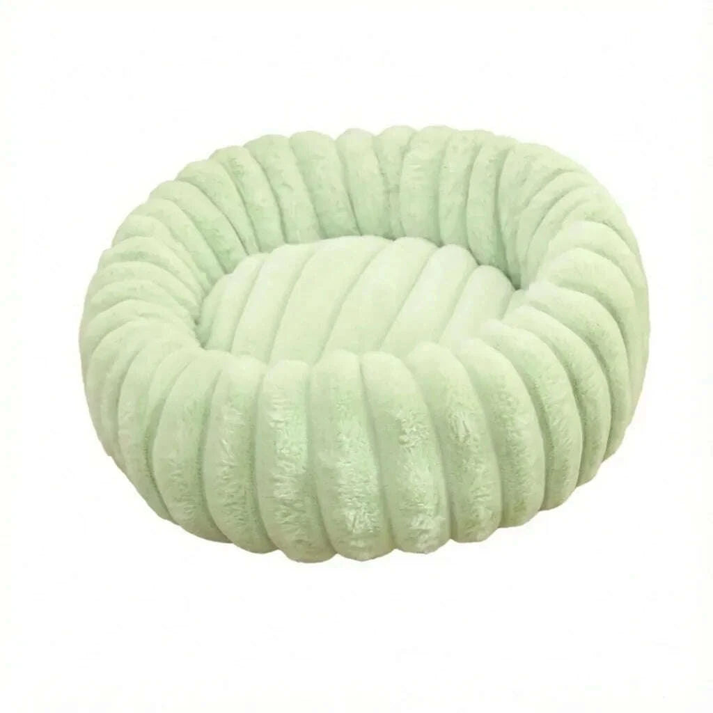 Panier rond pour chat en peluche vert pastel, bords matelassés en boudins, sur fond blanc