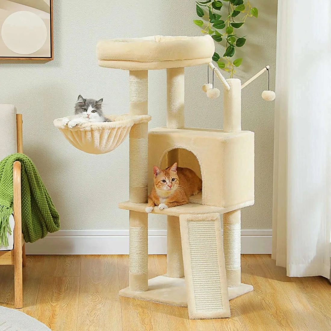 Arbre à chat beige dans un salon, un chaton gris dans le hamac et un chat roux allongé à l'entrée de la niche