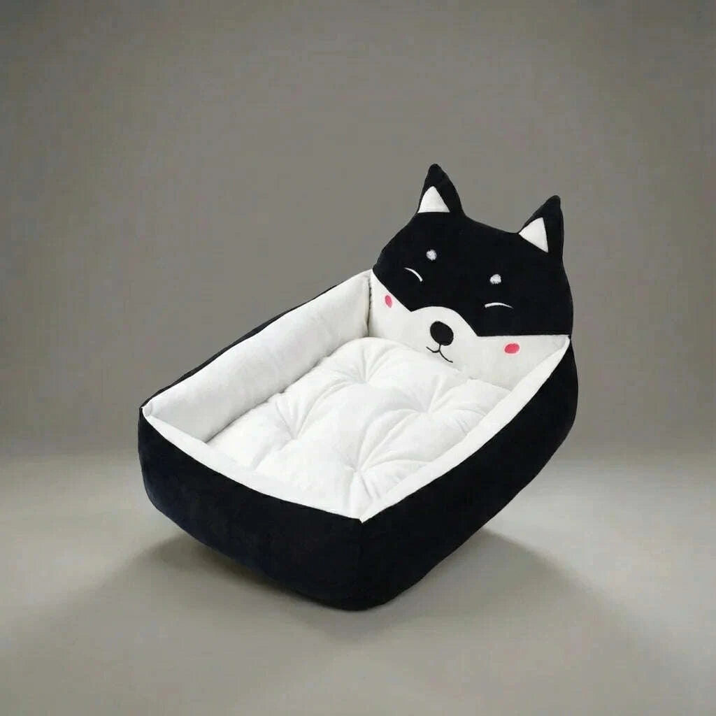 Corbeille douillette noire au coussin blanc matelassuré et à la tête brodée, posée sur un fond gris uni