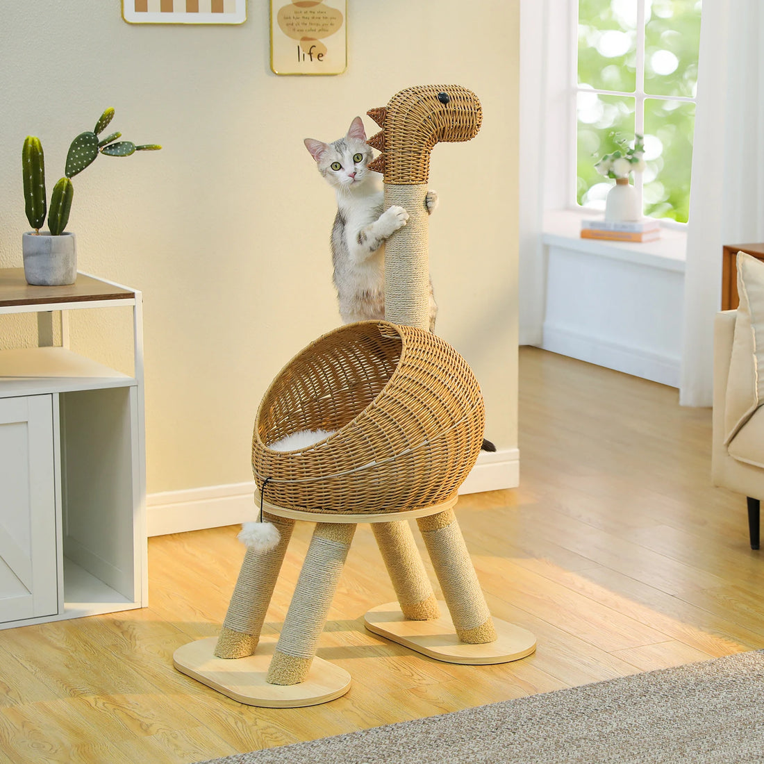 Chat tigré gris et blanc debout contre le poteau en sisal du griffoir dinosaure, dans un salon clair