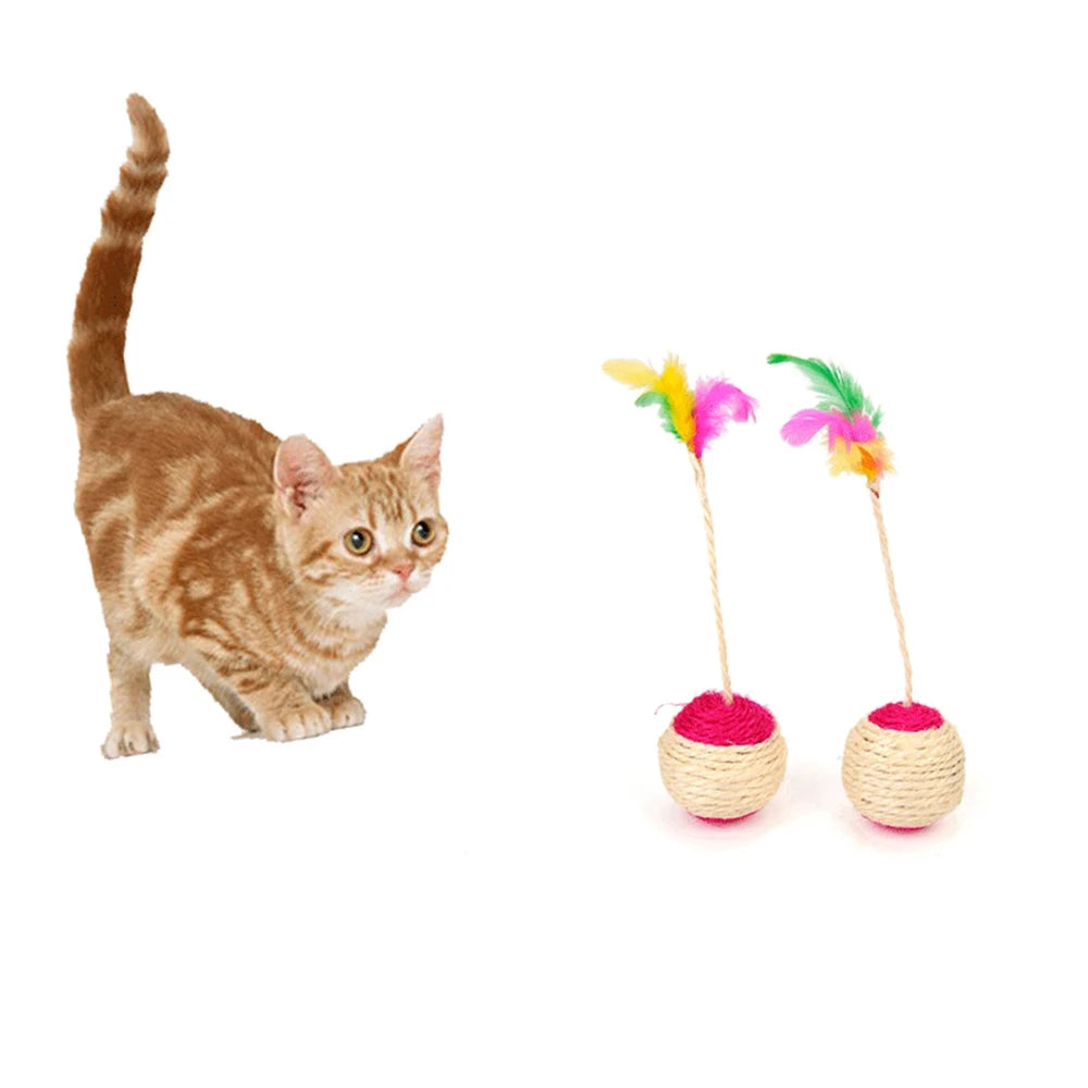 Chat roux tigré près de deux balles en sisal à tige, plumes multicolores et dessus rose fuchsia