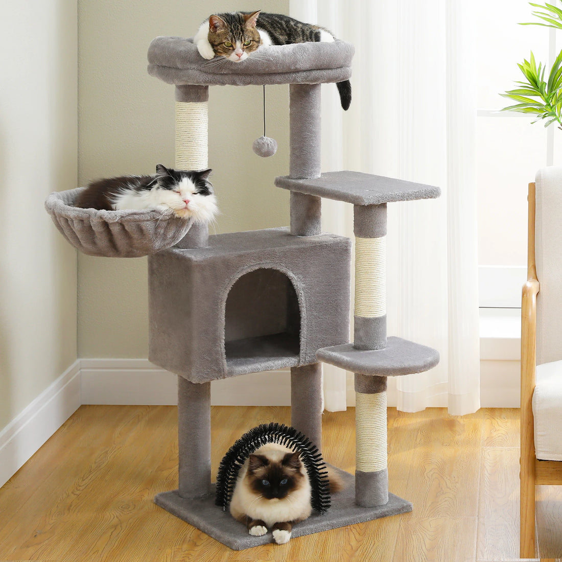 Arbre à chat gris clair dans un salon : trois chats se reposent sur le plateau, dans le hamac et sous l'arche