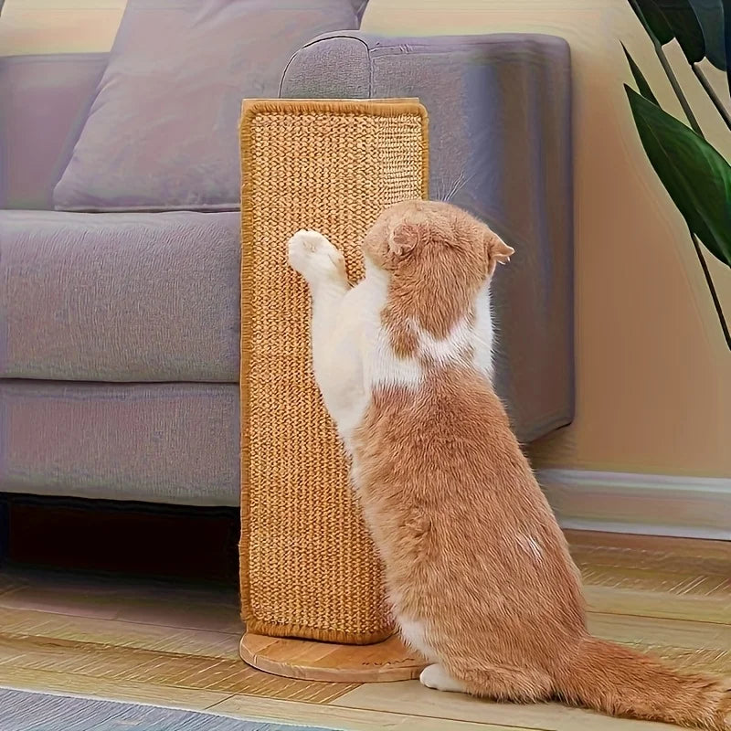 Chat roux et blanc debout contre un poteau griffoir en sisal sur socle en bois, devant un canapé gris