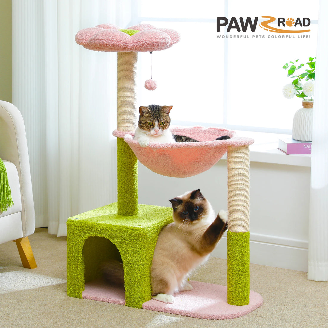 Arbre à chat fleur rose et vert dans un salon, un chat tigré dans le hamac et un ragdoll qui griffe le poteau
