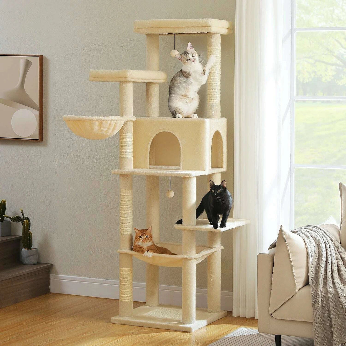 Grand arbre à chat beige dans un salon lumineux, chatons sur la niche, le hamac et la plateforme