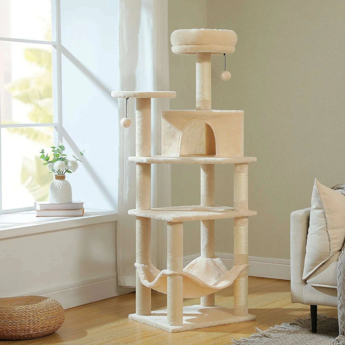 Beige cat tree by a sunny window between an armchair and light hardwood flooring