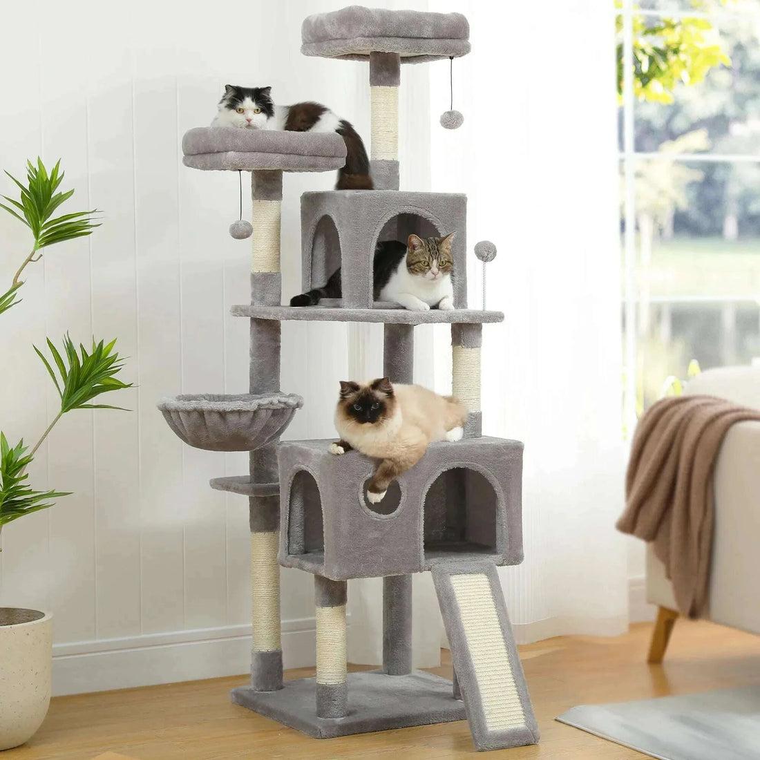 Meuble griffoir pour chat gris dans un salon, avec trois chats sur les plateaux et dans les niches