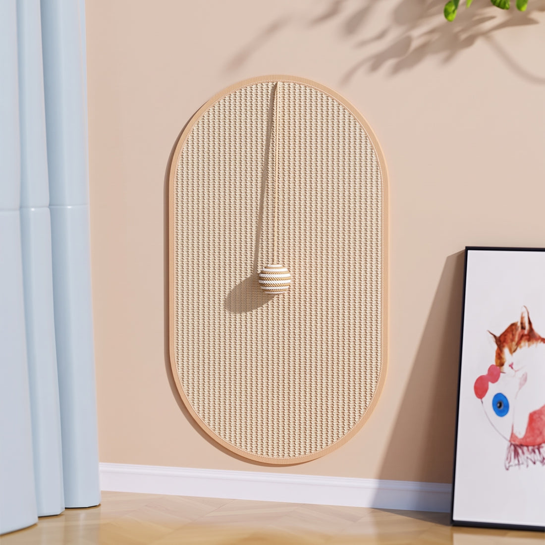 Grand tapis à gratter ovale en sisal accroché au mur rose pâle, avec sa balle de jeu à cordelette