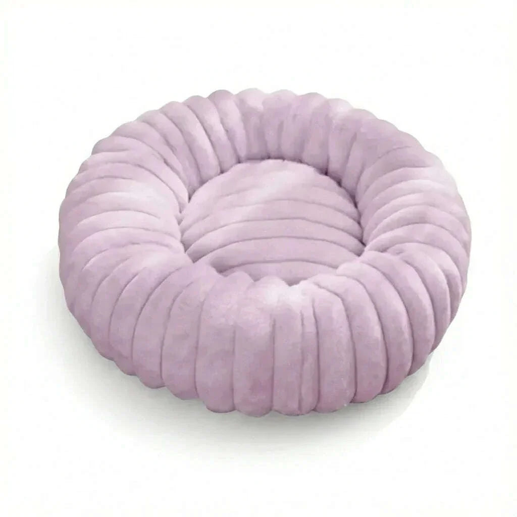 Lit rond pour chat rose lilas en peluche à bords côtelés, photographié en hauteur sur fond blanc