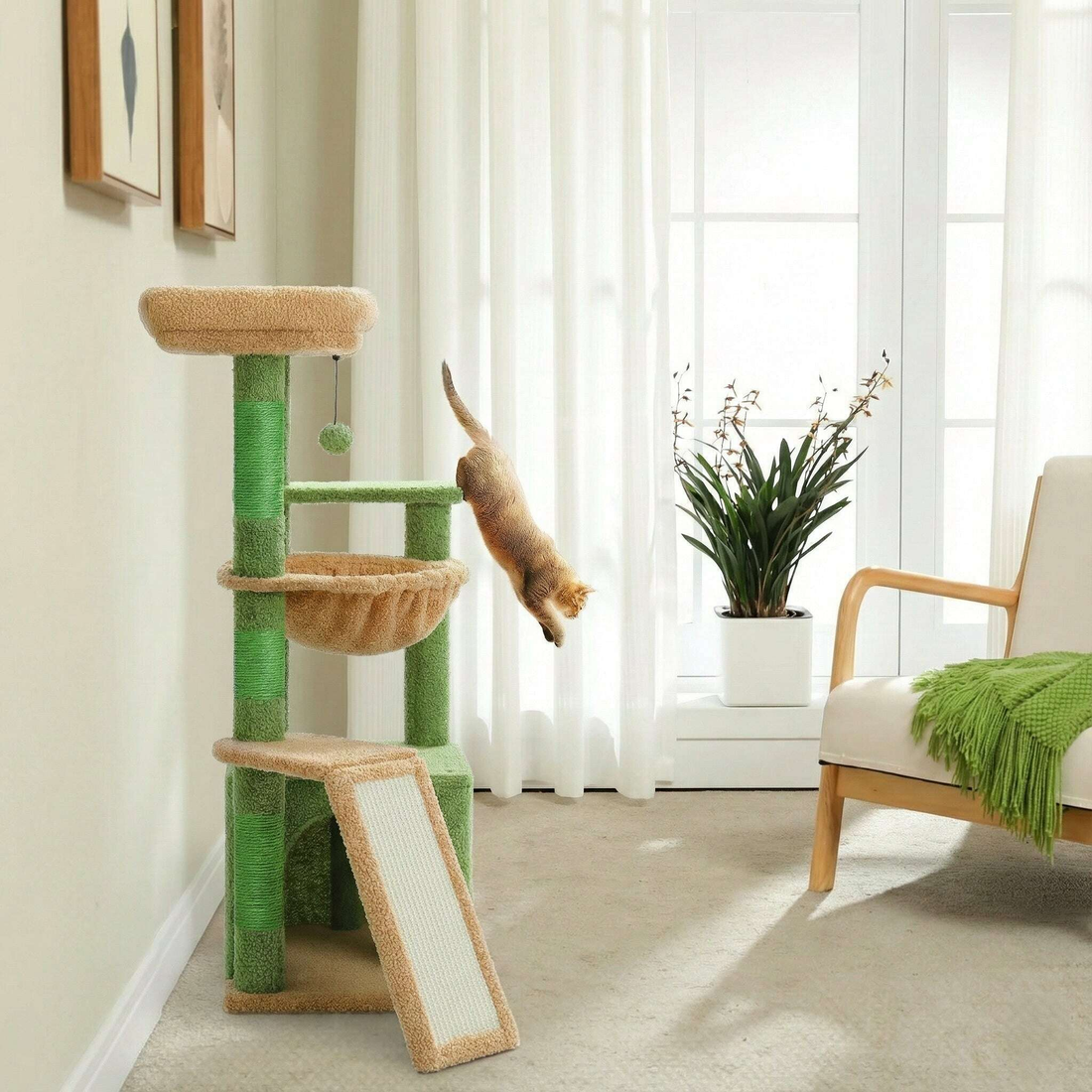 Chat roux en plein saut depuis le hamac d'un arbre à chat vert et beige, devant une fenêtre à voilage blanc