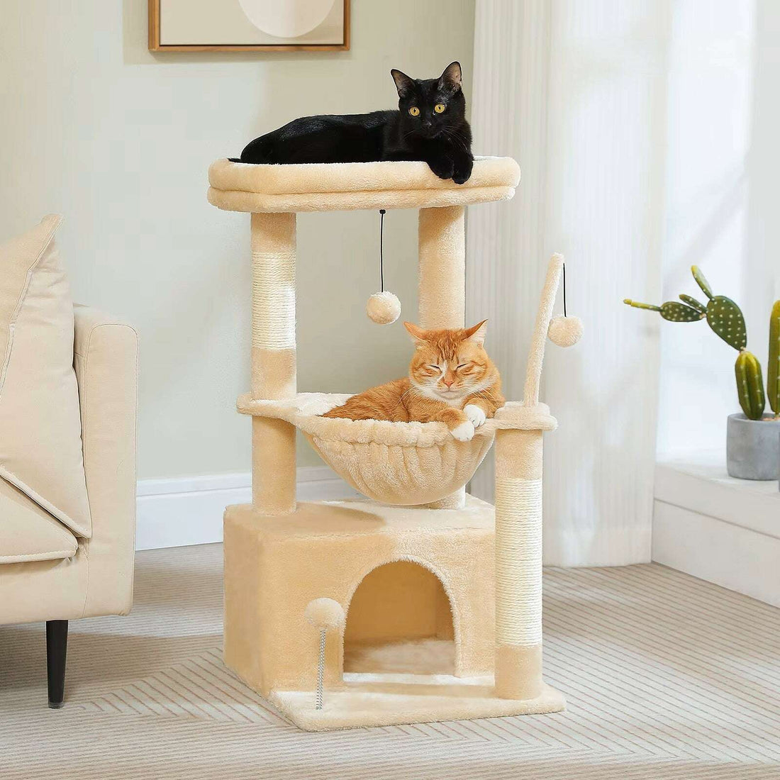 Arbre à chat compact beige dans un salon, chat noir en haut et chat roux endormi dans le hamac